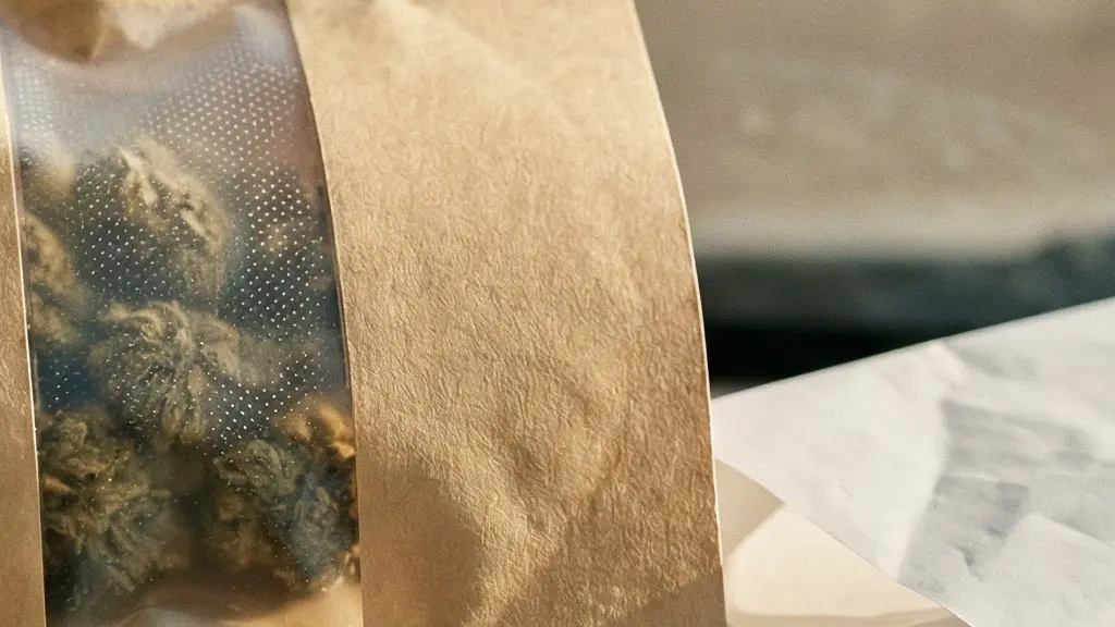 Gros plan sur un emballage scellé de fleurs de chanvre à côté d'un ticket de caisse plié, posés sur le tableau de bord d'une voiture