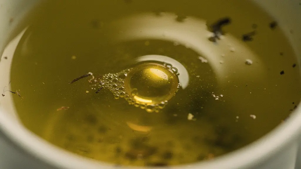 Gros plan macro sur une goutte d'huile dorée flottant à la surface d'une infusion aqueuse, illustrant la nature liposoluble du CBD